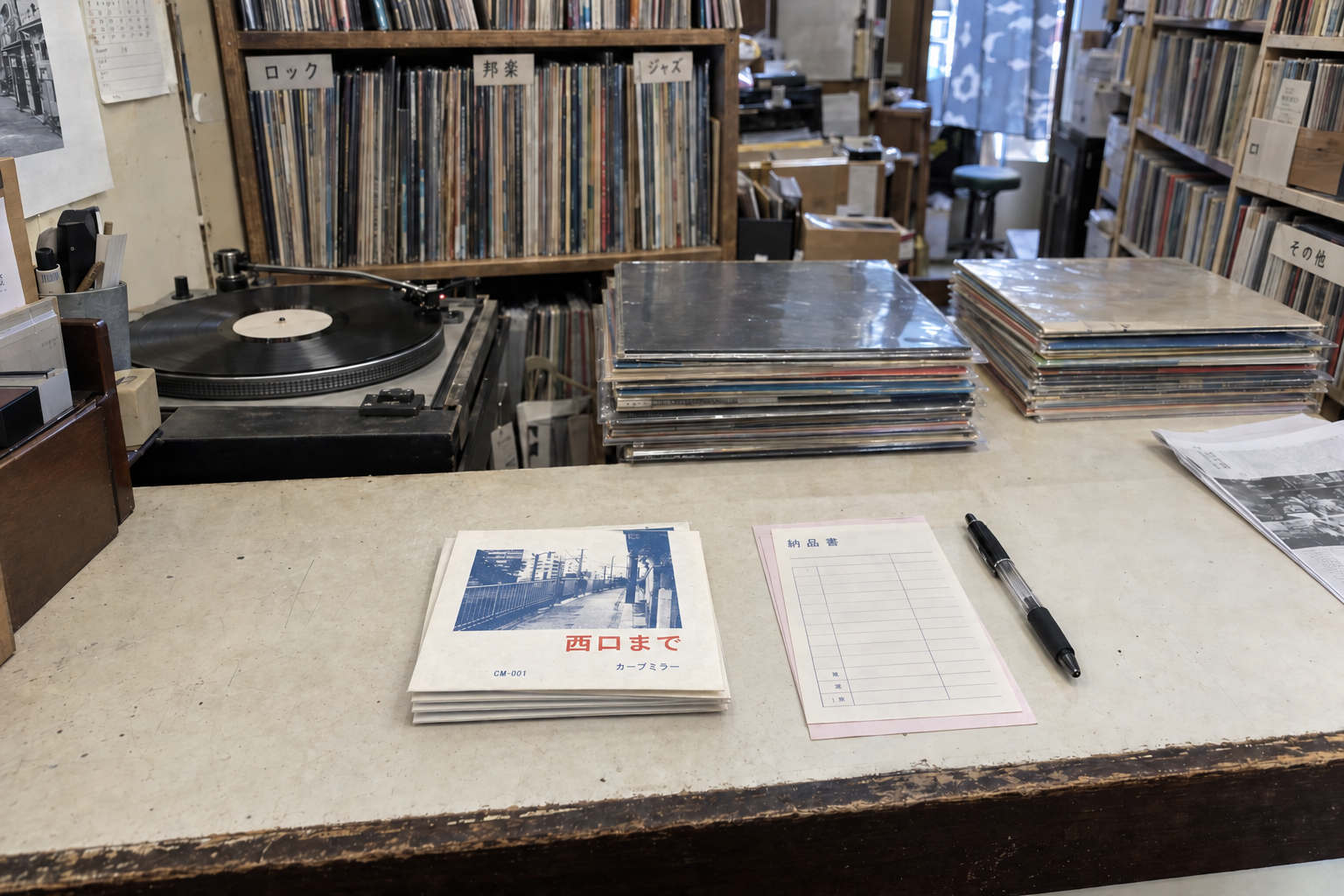 架空のレコード イトウのカウンター。委託盤の束と納品書、検盤用のプレーヤー